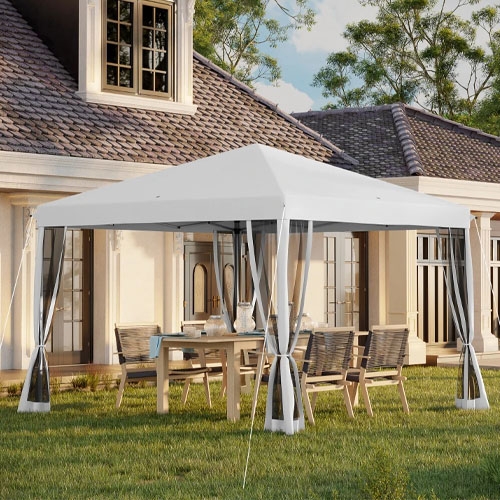 A white canopy tent with transparent curtains is set up in a backyard over a dining table and chairs, near a house with large windows and a tiled roof.