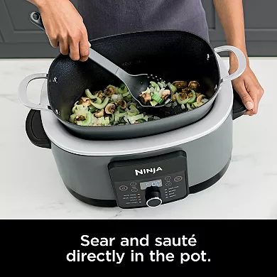 A person is sautéing mushrooms in a Ninja Foodi Multi-Cooker with a digital display.