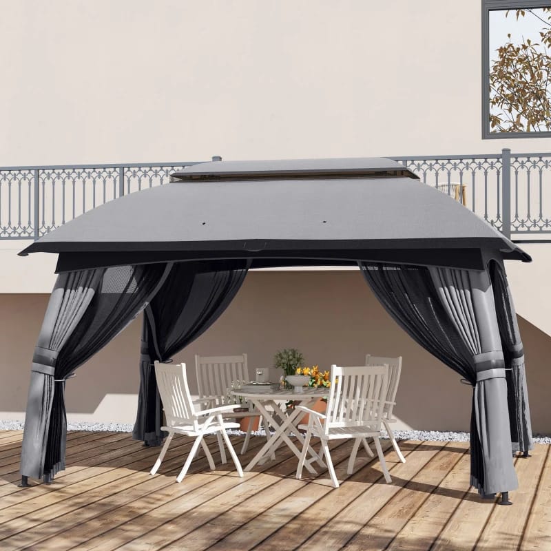 A gazebo with a gray canopy and black net curtains is set up on a wooden deck, sheltering a white outdoor dining table and chairs.