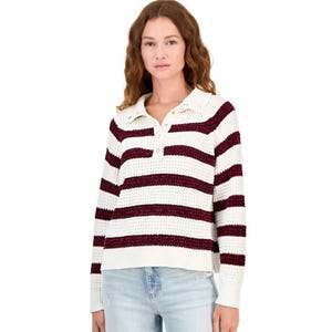 A woman wearing a white and burgundy striped collared sweater with buttons, paired with light blue jeans.