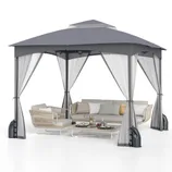 A patio set includes a large gazebo with a gray canopy and curtains, a wicker chair, a cushioned sofa, and a low coffee table with decorative items.