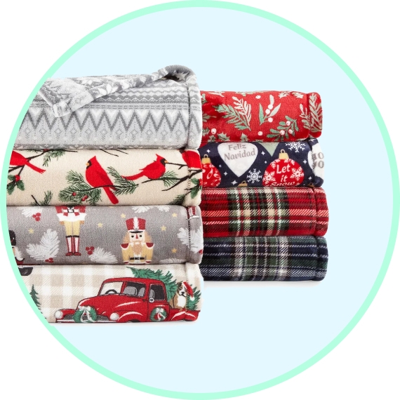 A stack of folded holiday-themed fabric with various Christmas patterns such as trees, cars, and traditional sayings.