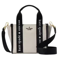 A Kate Spade New York handbag with black and white canvas, featuring \“Kate Spade New York\“ text on the straps and gold hardware.