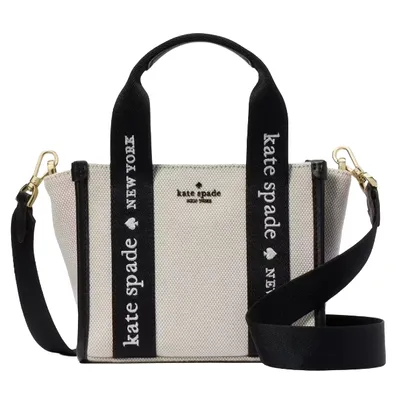 A Kate Spade New York handbag with black and white canvas, featuring \“Kate Spade New York\“ text on the straps and gold hardware.