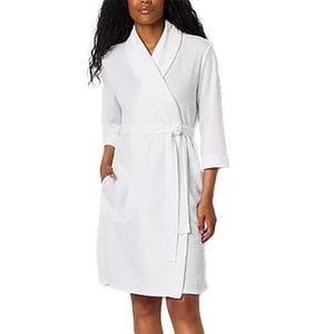 A white waffle knit robe with a knee-length design, featuring three-quarter sleeves, a shawl collar, a tie belt, and side pockets.