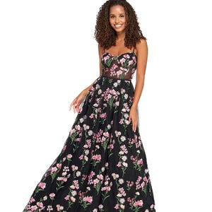A black tulle ballgown with pink and green floral embroidery, featuring a fitted bodice with thin straps and a sheer waist detail.