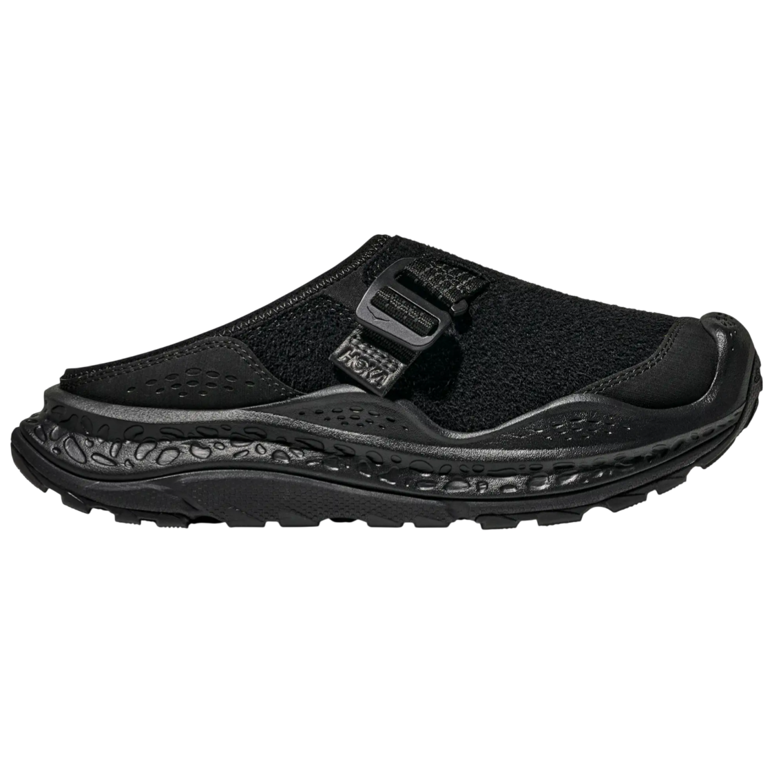 A black slip-on shoe featuring a chunky, textured sole and an adjustable strap, designed for comfort and support.