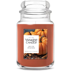 Yankee Candle featuring a Spiced Pumpkin scent in a clear jar, showcasing images of pumpkins and spices on the label.