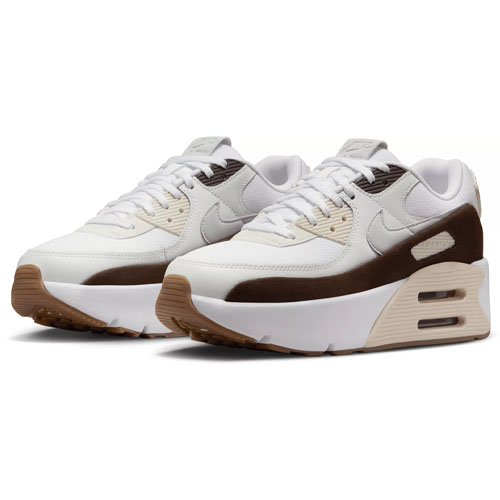 A pair of Nike Air Max 90 LV8 sneakers with a white upper, beige overlays, and a dark brown rubber outsole featuring visible Air cushioning.