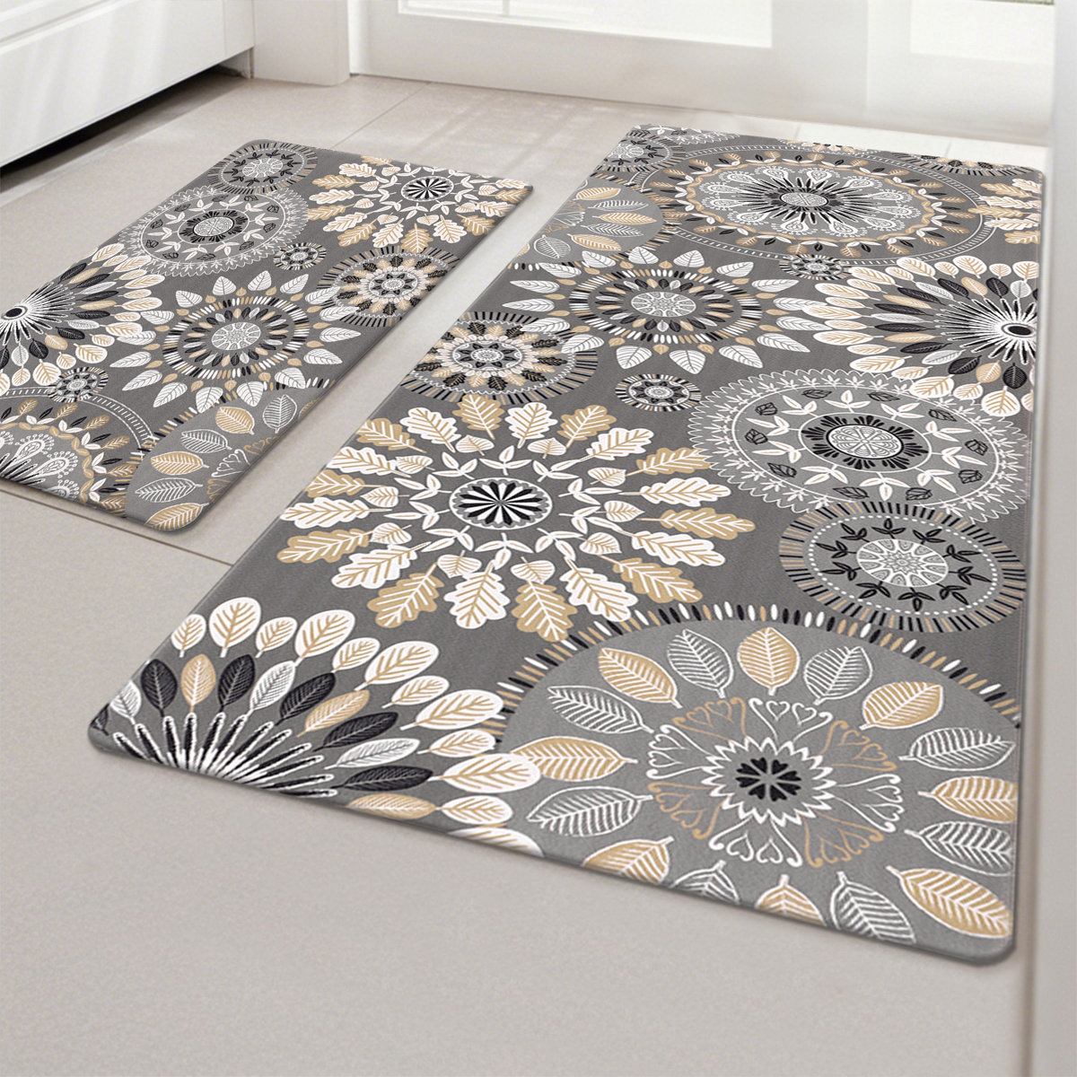Two gray rugs with intricate mandala and leaf patterns in white, beige, and black adorn a light-colored floor.