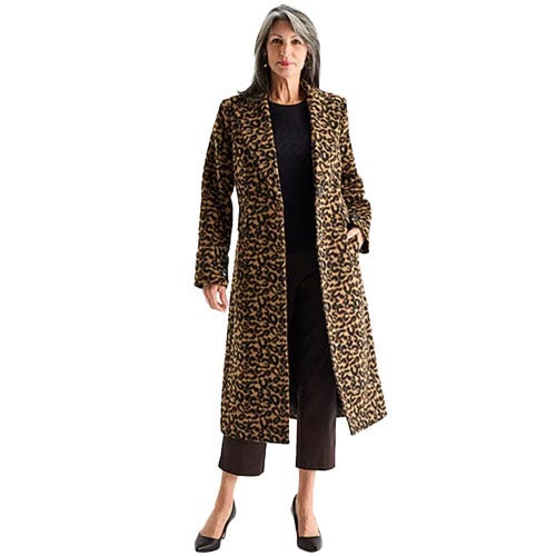 A woman is wearing a long leopard print coat over black pants and a black top, paired with black heels.