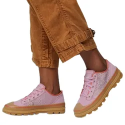 Person wearing pink lace-up shoes with floral patterns and gum soles, paired with rolled-up brown pants.