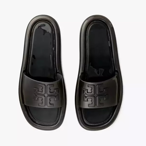 A pair of black slide sandals with a prominent embossed logo on the strap.