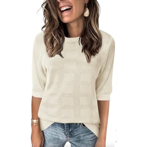 Women's short-sleeve ivory sweater features a knitted grid pattern with ribbed cuffs and hem, paired with light blue jeans and accessorized with gold earrings and bracelets.