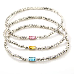 Three silver beaded stretch bracelets each featuring a rectangular gemstone: pink, yellow, and blue.