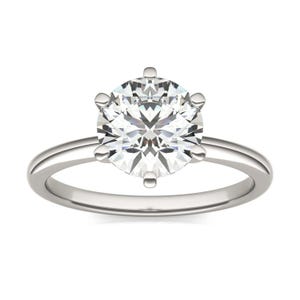 A silver ring featuring a round, solitaire diamond set in a six-prong setting with a simple band.