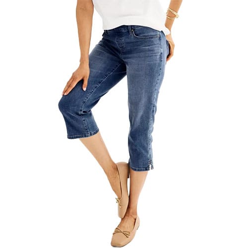 A person is wearing blue cropped jeans paired with beige ballet flats and a white top.