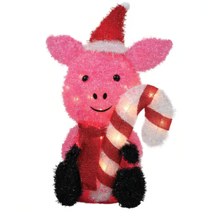 A pink light-up pig figurine wearing a Santa hat, black mittens, and a red scarf, holding a striped candy cane.