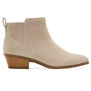 Beige ankle booties with a low stacked heel and side pull tab, featuring a perforated design on the upper section.