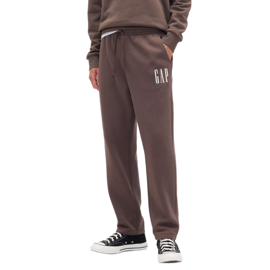 Brown sweatpants with \“GAP\“ logo, featuring an elastic waistband, drawstring, and side pockets; paired with black and white sneakers.