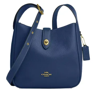 Blue leather Coach handbag with a gold-tone turn-lock closure and adjustable strap, featuring the Coach logo embossed on the front.