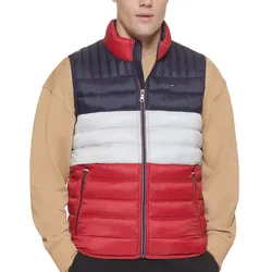 A color-blocked puffer vest featuring navy, white, and red horizontal stripes with a front zipper, worn over a beige sweatshirt.