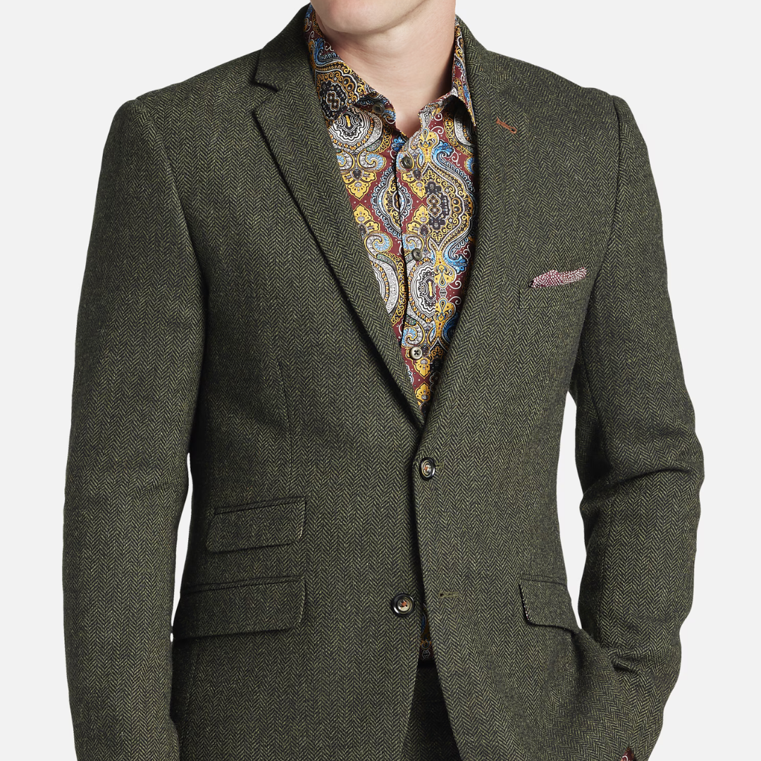 A man wearing a herringbone patterned blazer, patterned dress shirt, and a pink pocket square.