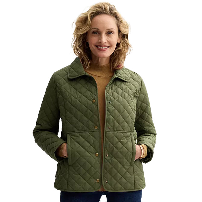 A woman wearing a quilted olive-green jacket with a collar and button-up front, paired with a mustard turtleneck and dark pants.