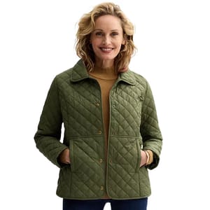 A woman wearing a quilted olive-green jacket with a collar and button-up front, paired with a mustard turtleneck and dark pants.