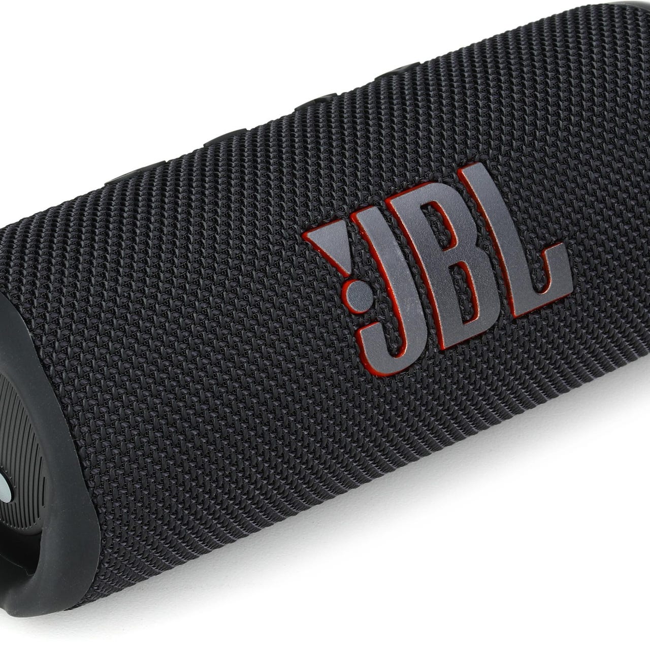 A cylindrical portable JBL Flip 6 speaker with a black textured fabric cover and the JBL logo in red.