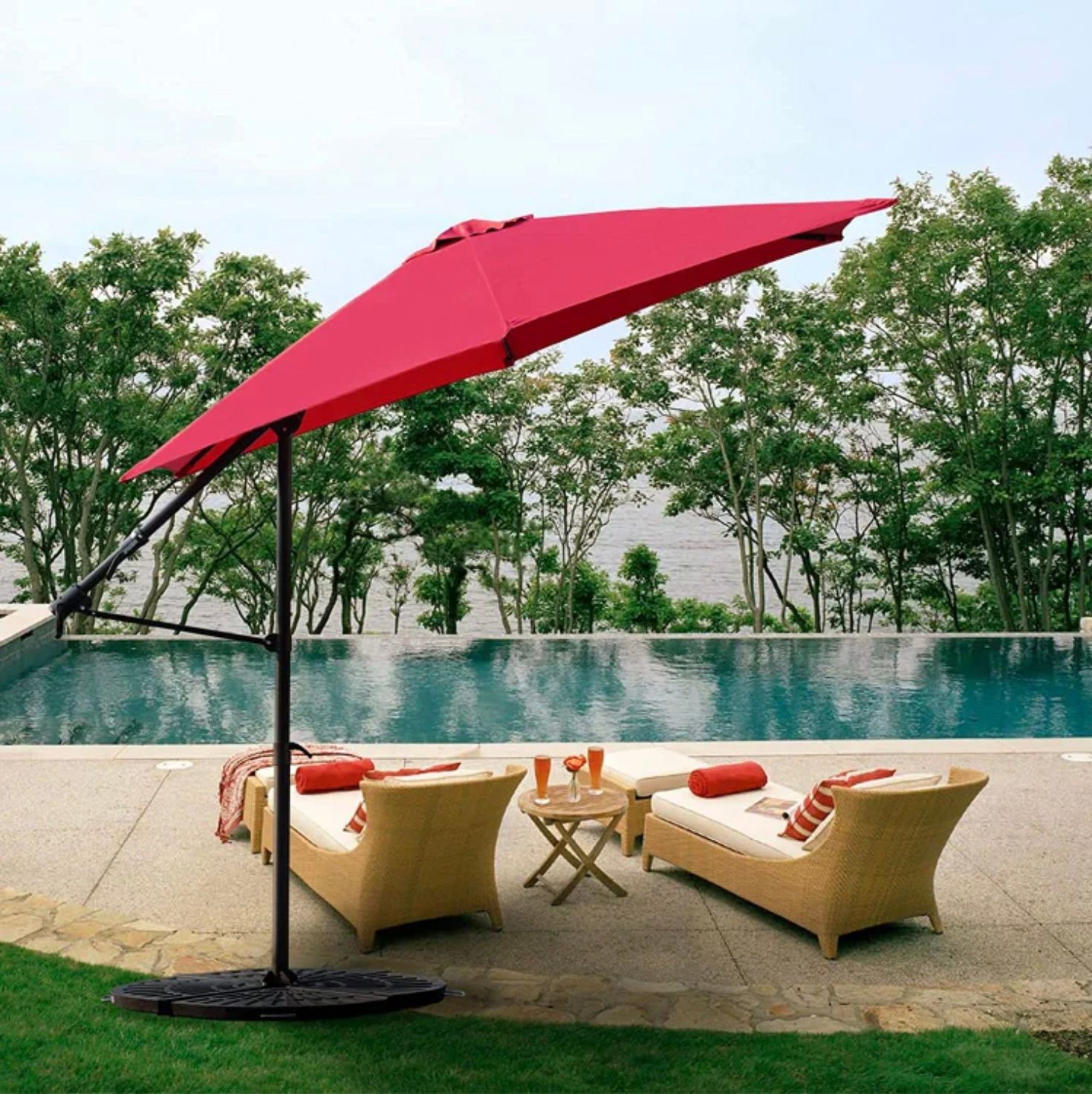 A red patio umbrella, outdoor furniture with cushions, and a poolside setting.