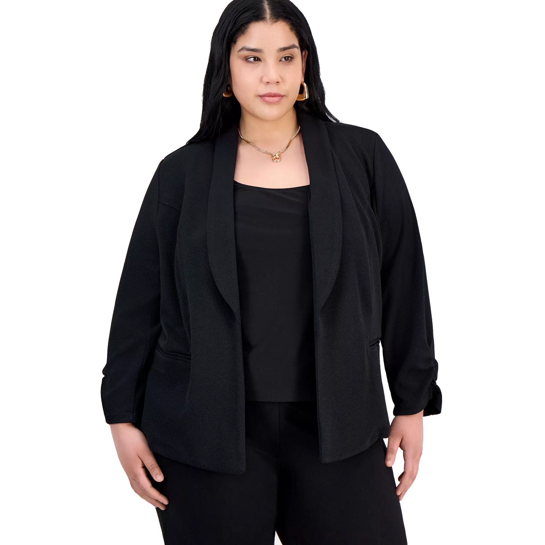 A woman is wearing a black blazer over a black top with matching black pants, accessorized with gold jewelry.
