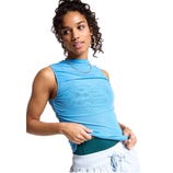 A person wearing a sleeveless blue mesh top over a green sports top paired with light blue drawstring pants. They accessorize with a chain necklace and hoop earrings.