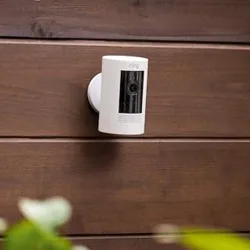 A security camera is mounted on a wooden wall, highlighting its versatile mounting options.