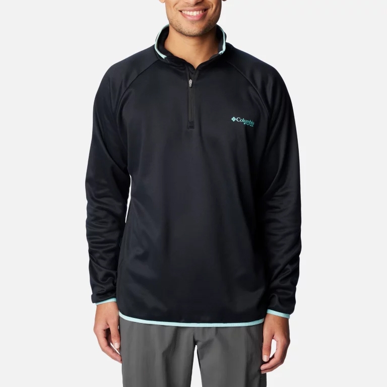 A man wearing a black long-sleeve pullover with a logo on the chest and teal accents at the collar and hem.