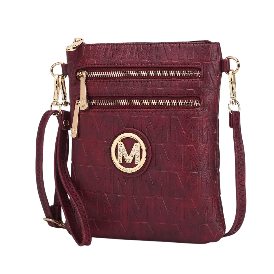 Maroon crossbody bag with embossed \“M\“ pattern, featuring a gold circular logo with an \“M\“ and rhinestones, two front zip pockets, and a detachable strap.
