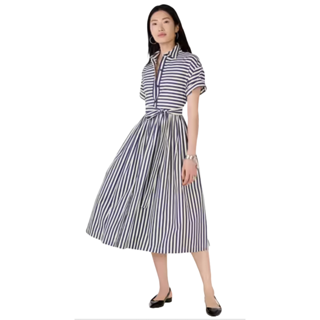A woman is wearing a striped, short-sleeve, belted midi dress paired with black flats.