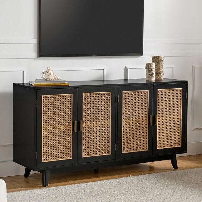 A black sideboard with natural rattan cabinet doors is topped with decorative items, positioned beneath a wall-mounted TV in a room with white paneled walls.