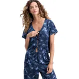 A woman is wearing a short-sleeved, deep V-neck top and pants set with a blue floral pattern, featuring ties at the front and an elastic waistband.