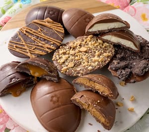 12pk Landies Candies Truffle Eggs feature an assortment of chocolate eggs filled with caramel, peanut butter, and cream. Toppings include nuts, cookie crumbs, and drizzle for variety.