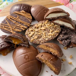 12pk Landies Candies Truffle Eggs feature an assortment of chocolate eggs filled with caramel, peanut butter, and cream. Toppings include nuts, cookie crumbs, and drizzle for variety.