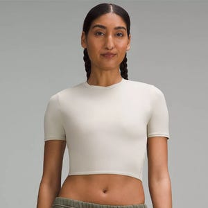 Woman wearing a plain, short-sleeved, cropped top with high-waisted green pants.