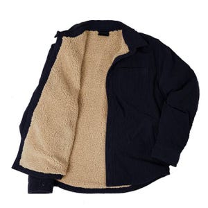A black corduroy jacket with beige sherpa lining, featuring a front pocket and buttoned cuffs.
