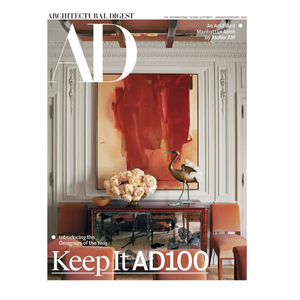 Architectural Digest cover showing an art-filled room by Atelier AM with a striking red abstract painting, floral arrangement, and decorative sculpture on a mirrored console, accompanied by stylish seating.