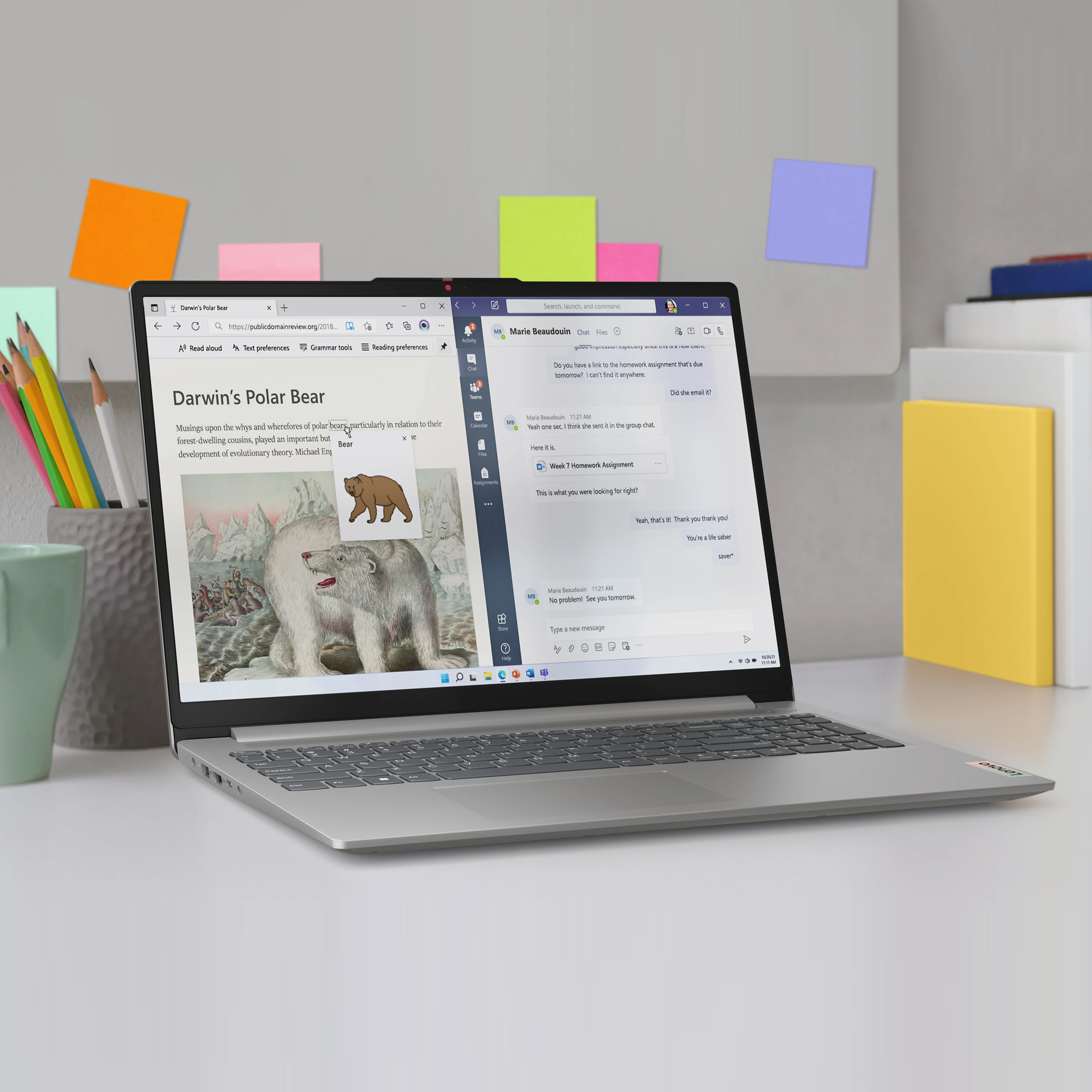 A silver Lenovo IdeaPad with a 15.6\“ display, dual-screen feature extended, sits on a desk surrounded by sticky notes and office supplies.