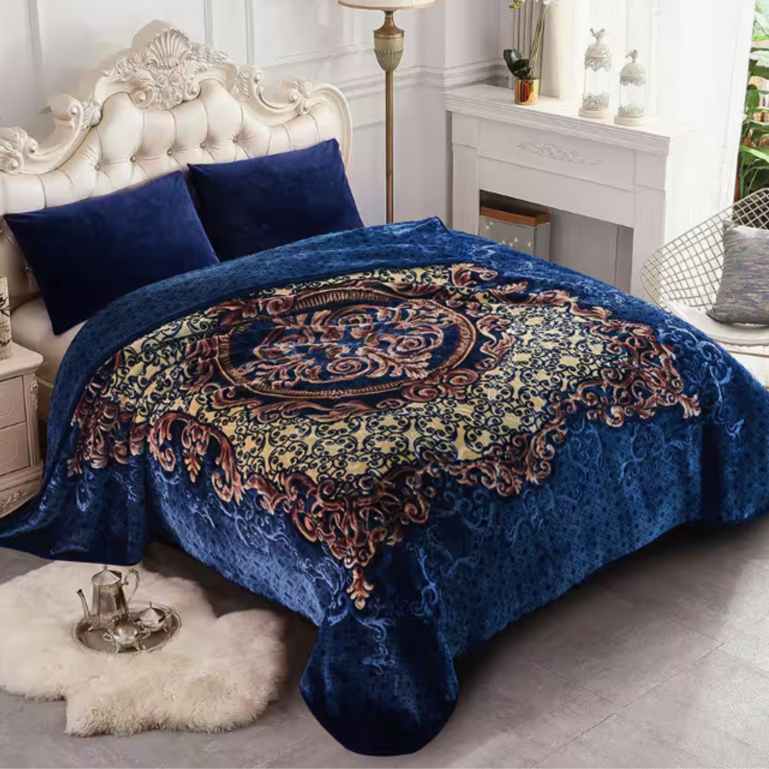 A luxurious, plush Raschel mink blanket with an ornate central design in gold and intricate patterns on a royal blue background, draped over a bed with matching dark blue pillows in an elegant bedroom setting.