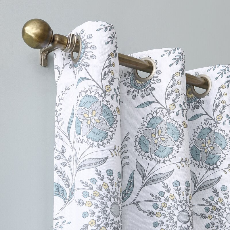 Patterned curtain with floral design hanging on a bronze-colored curtain rod.