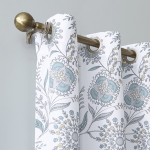 Patterned curtain with floral design hanging on a bronze-colored curtain rod.