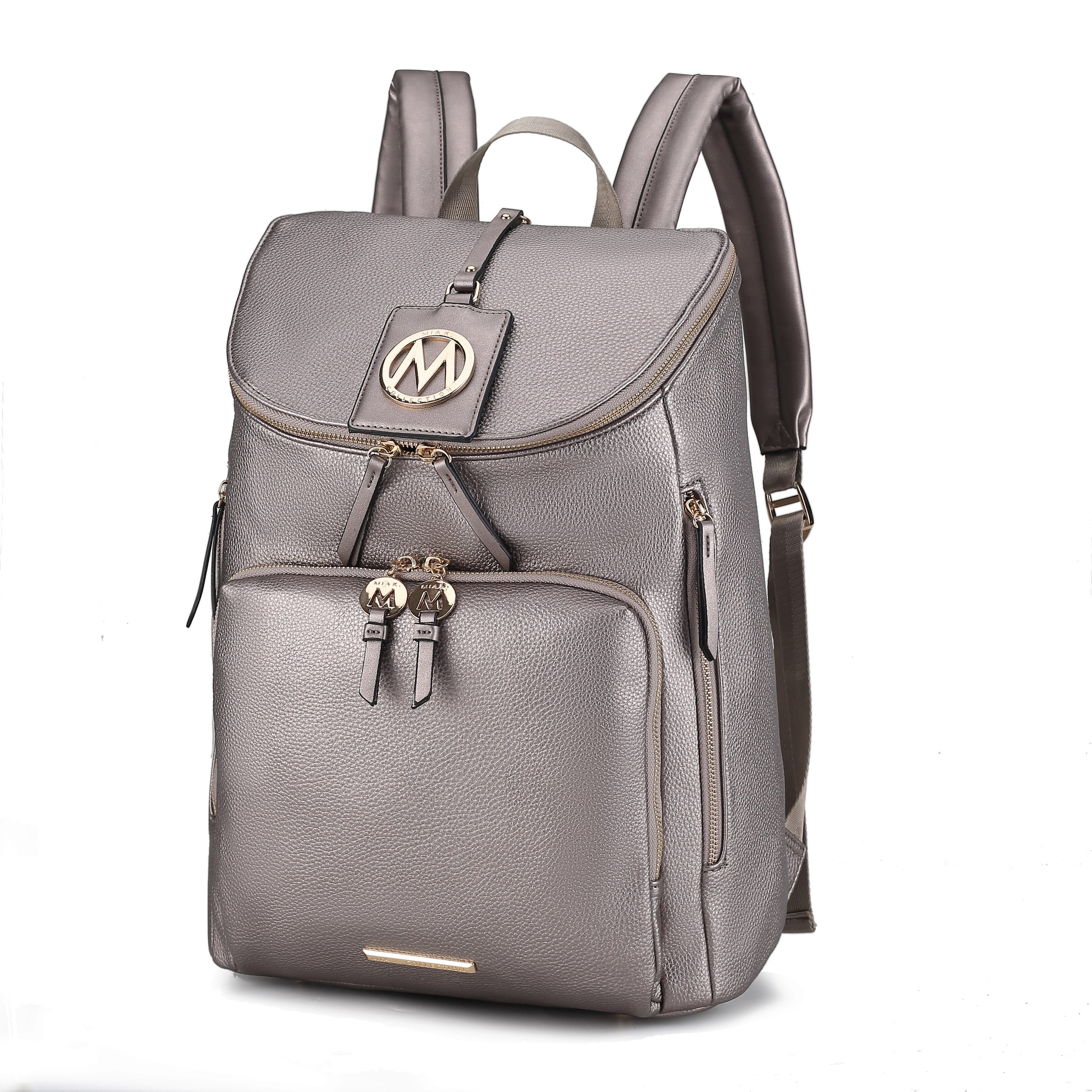 A stylish gray leather backpack with a flap top, gold-tone zippers, and a round emblem featuring the letter \“M\“. It includes a front pocket and padded shoulder straps for comfortable carrying.