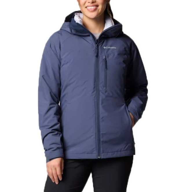 A woman is wearing a blue Columbia jacket with a hood and a zipper closure. The jacket features side pockets and a chest pocket, paired with black pants.